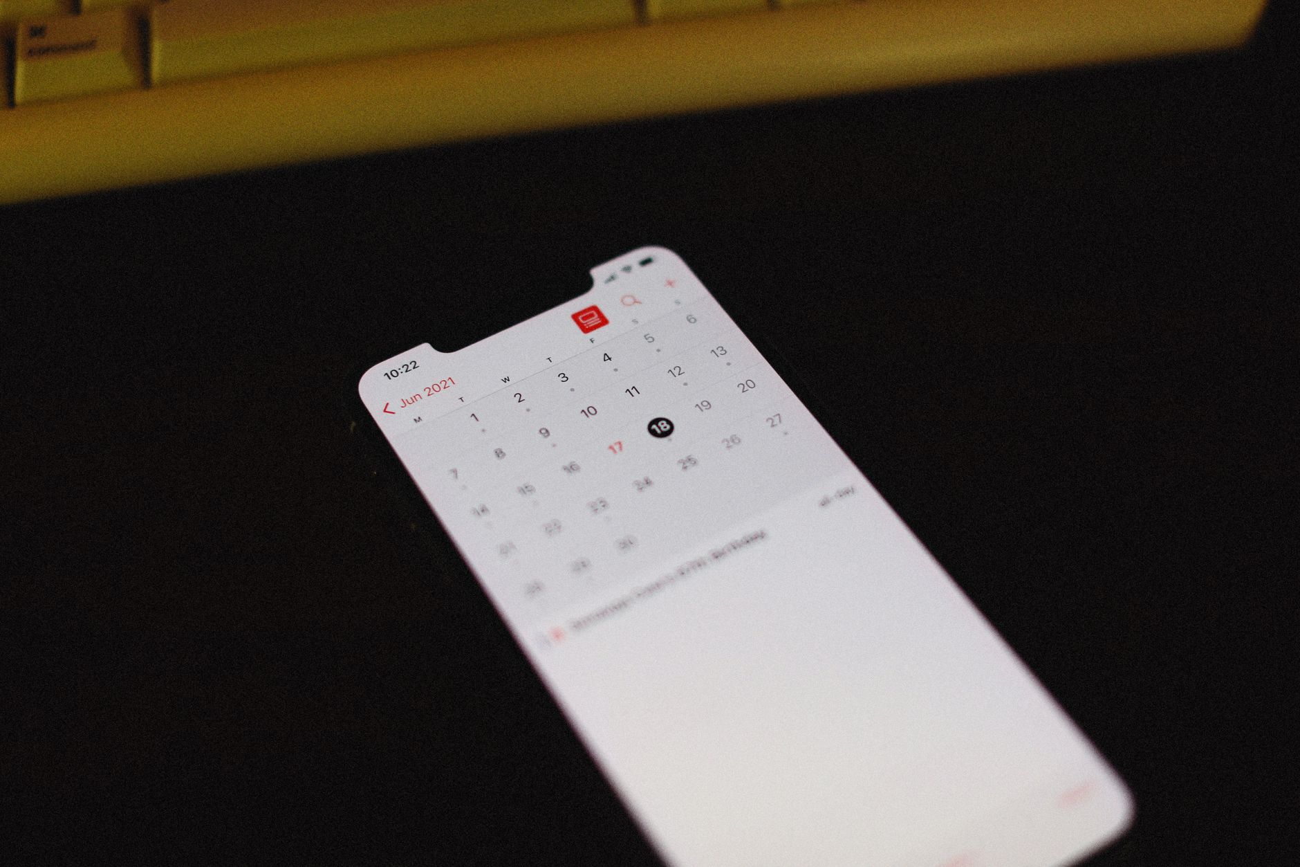 Smartfon z aplikacją kalendarza na ciemnym tle, widoczny czerwiec 2021