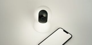 Jak wykorzystać sztuczną inteligencję i Internet Rzeczy do poprawy bezpieczeństwa w inteligentnym domu Kamera bezpieczeństwa smart home obok smartfona na białym tle