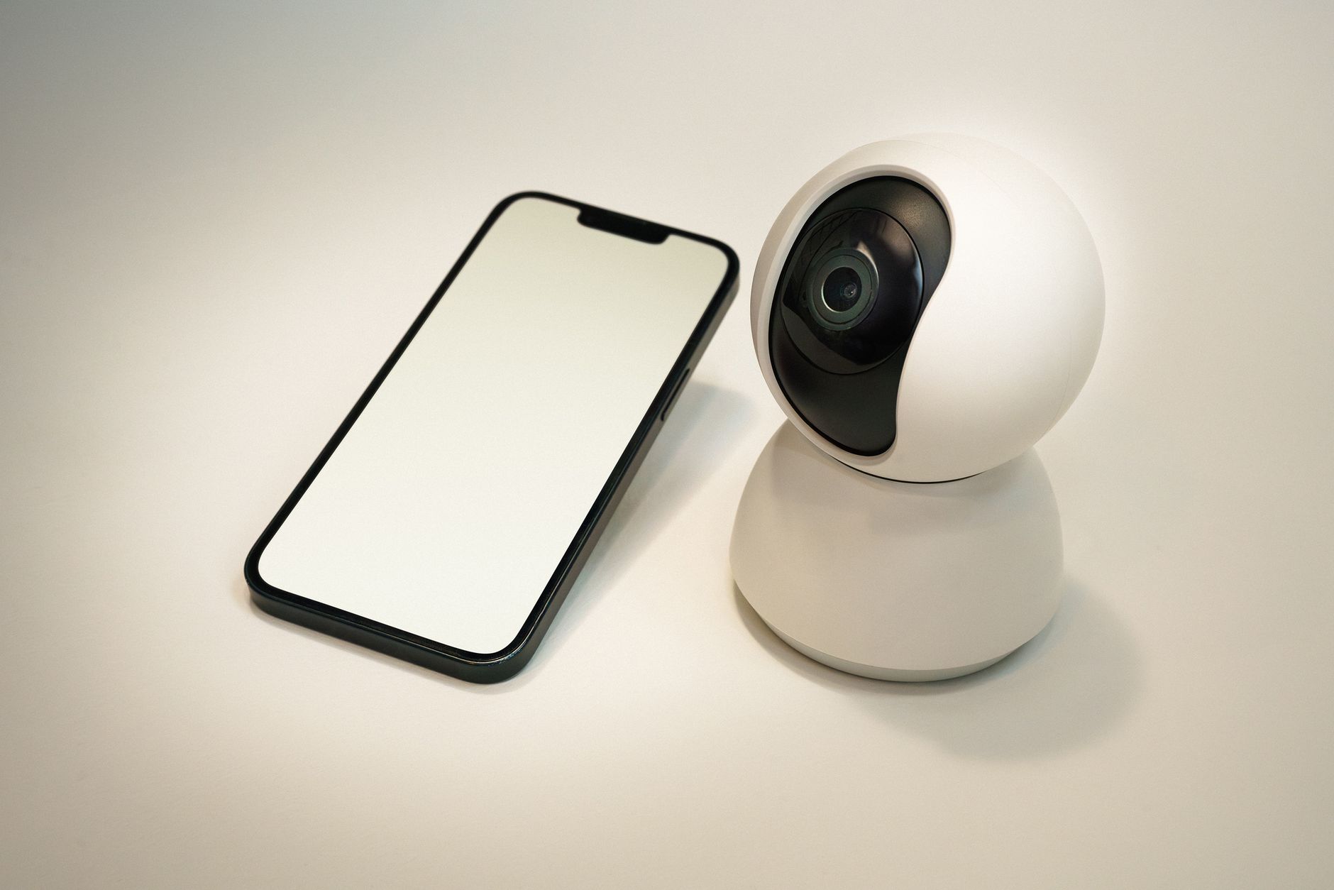 Kamera bezpieczeństwa smart home obok smartfona z pustym ekranem