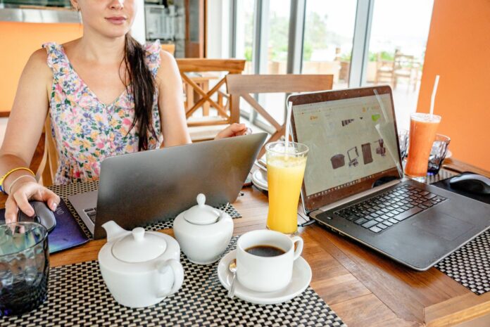 Kobieta pracuje na laptopach w kawiarni przy napojach i czajniczkach